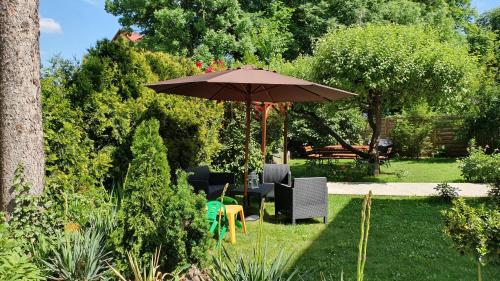 an umbrella in a garden with chairs and a table at Willa Nad Potokiem in Kudowa-Zdrój