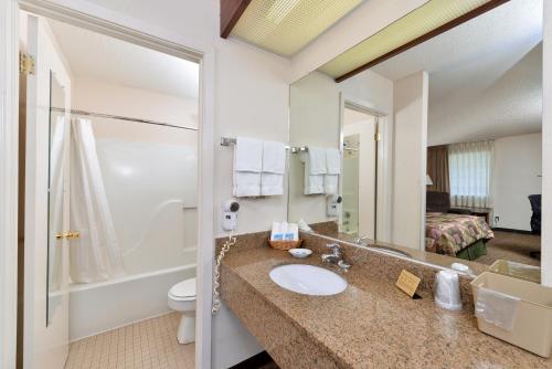 La salle de bains est pourvue d'un lavabo, de toilettes et d'un miroir. dans l'établissement The Heritage Inn, Inc, à Huntingdon