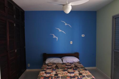 un dormitorio con una pared azul con pájaros pintados en él en Apto praia Martim de Sá, en Caraguatatuba