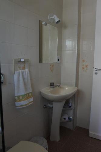 a bathroom with a sink and a mirror and a toilet at Apto praia Martim de Sá in Caraguatatuba