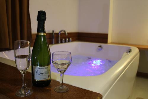 a bottle of champagne and two glasses in a bath tub at Hotel Miramar in Huarmey