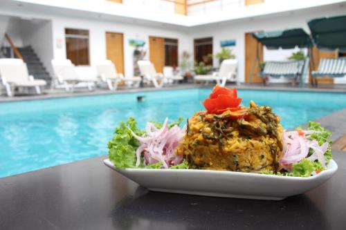 a plate of food on a table next to a pool at Hotel Miramar in Huarmey