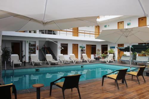 a pool with chairs and umbrellas in a hotel at Hotel Miramar in Huarmey