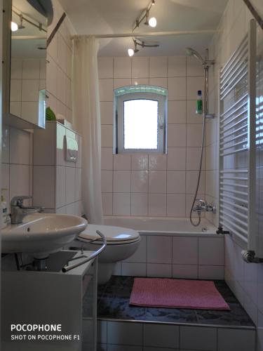 a bathroom with a sink and a tub and a toilet at Ferienwohnung Allgäuglück in Waltenhofen