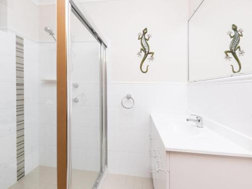 a white bathroom with a shower and a sink at Fairholme 12 in Tuncurry