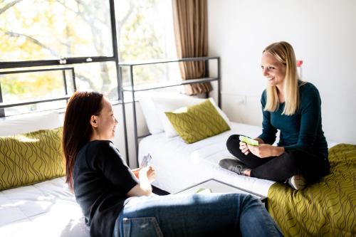 twee vrouwen die op een bank zitten te praten in een woonkamer bij YMCA Hostel in Auckland