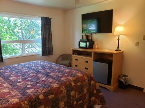a hotel room with a bed and a television at Bridge Street Inn in Baker City