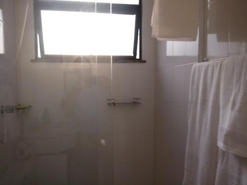 La salle de bains est pourvue d'une douche avec une fenêtre et un rideau de douche. dans l'établissement Conheça Caxambu e sua Natureza, à Caxambu