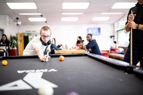 a man is playing a game of pool at YMCA Hostel in Auckland