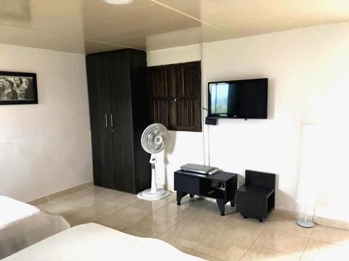 a bedroom with a bed and a tv and a fan at Finca El Bazar in Montenegro