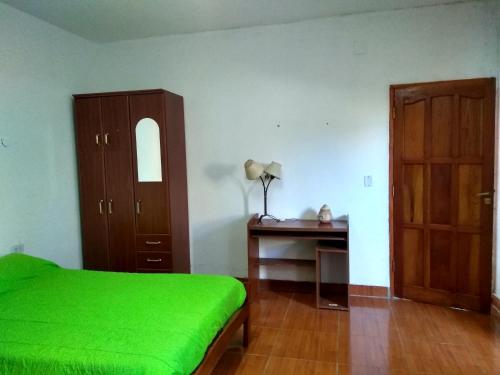 a bedroom with a green bed and a desk at Hostal killari in Cafayate