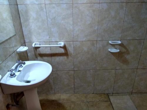 a bathroom with a white sink and a tiled wall at Hostal killari in Cafayate