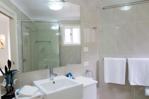 a white bathroom with a sink and a shower at Mollymook Beach Waterfront in Mollymook