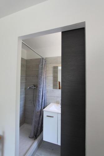 La salle de bains est pourvue d'une douche et d'un lavabo blanc. dans l'établissement CASAMACCE Studio climatisé avec terrasse, small comfortable apartment free parking, air-conditioned & Wifi, à Corte
