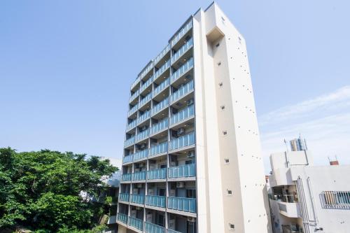 a tall white building with blue windows at Hotel Urbansea 2 Matsuo in Naha