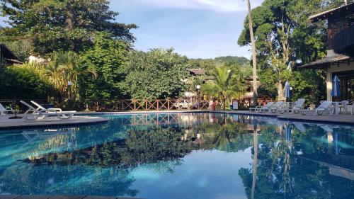 a swimming pool with white chairs and trees at Casa Canto do Mar Maresias 2 in Maresias