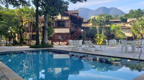 a resort with a swimming pool with chairs and a building at Casa Canto do Mar Maresias 2 in Maresias