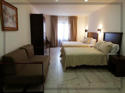 テパティトラン・デ・モレロスにあるHotel Real Victoriaのベッド2台とソファが備わるホテルルームです。
