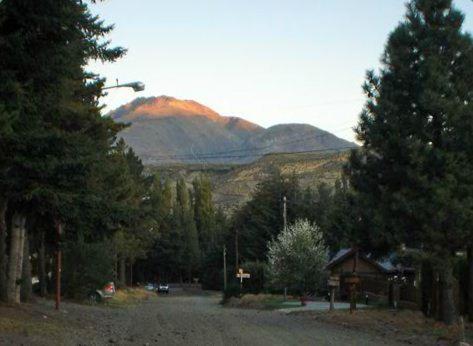 a road with a mountain in the distance with trees at Rincon del Sur in Esquel