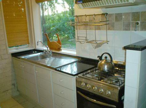 La cocina está equipada con fogones, fregadero y hervidor de agua. en Rincon del Sur en Esquel