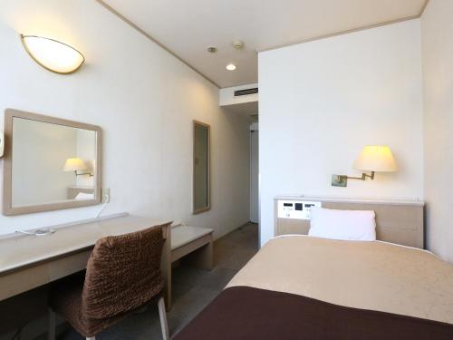 um quarto de hotel com uma cama, uma secretária e um espelho em Chino Sky View Hotel em Chino