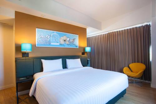 a bedroom with a large bed and a yellow chair at idoop Hotel Lombok in Mataram