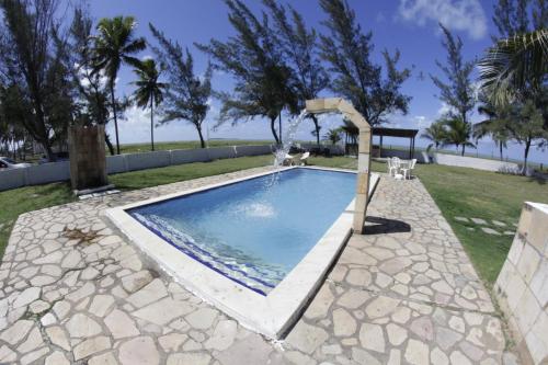 a swimming pool with a water fall in a yard at Pousada Cataventos in Sirinhaém