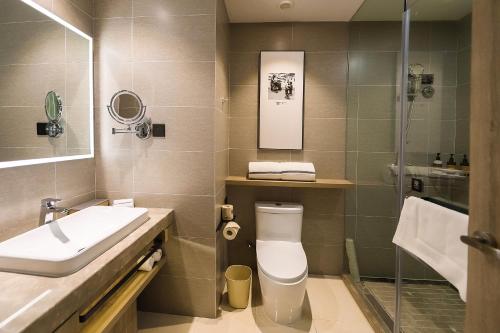 a bathroom with a toilet and a sink and a shower at Hilton Garden Inn Zhuji East in Shaoxing