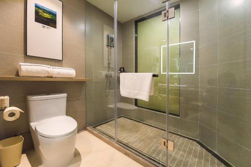 a bathroom with a toilet and a glass shower at Hilton Garden Inn Zhuji East in Shaoxing