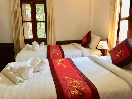 a hotel room with three beds with towels on them at Villay Vanh Place House in Luang Prabang