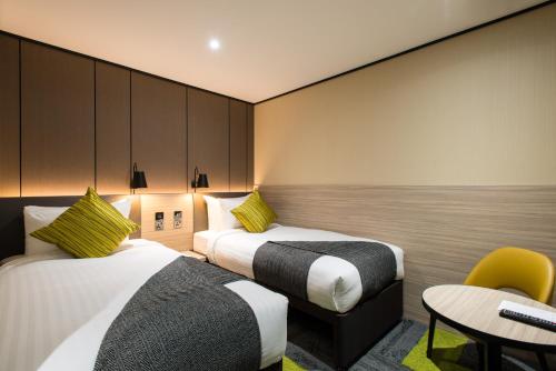 a hotel room with two beds and a table and a chair at Aerotel London Heathrow Airport, Terminal 2 & Terminal 3 in Hillingdon