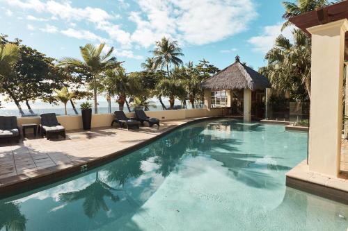 a swimming pool with chairs and a gazebo at Sea Change Beachfront Apartments in Trinity Beach