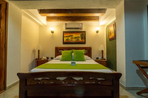 a bedroom with a bed with green pillows at Hotel Don Pedro De Heredia in Cartagena de Indias