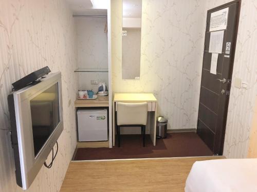 Kleines Zimmer mit einem TV und einem kleinen Tisch. in der Unterkunft Say Love Hotel in Taipeh