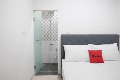 Un dormitorio con una cama con una almohada roja. en RedDoorz near Taman Palem en Yakarta