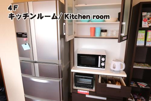 a kitchen with a refrigerator and a microwave at RED HELMET House & Sports Bar Hiroshima in Hiroshima