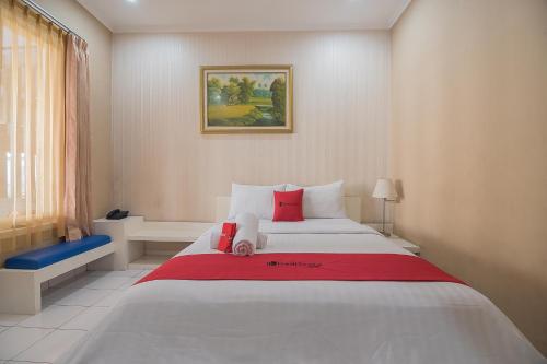 a bedroom with a large white bed with red pillows at RedDoorz at Amellia Pasteur Bandung in Bandung
