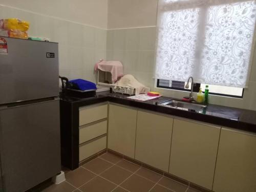 a kitchen with a refrigerator and a sink and a window at HOMESTAY SU in Marang