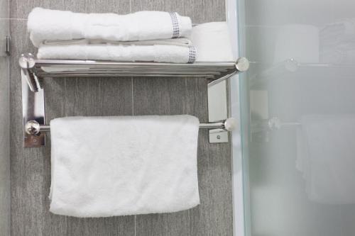 a stack of towels on a towel rack in a bathroom at Hanoi Bel Ami Hotel in Hanoi