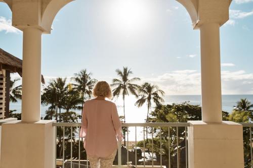 a woman standing on a balcony looking out at the ocean at Sea Change Beachfront Apartments in Trinity Beach