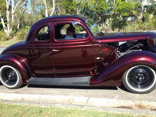 an old red car parked on the street with a man at XYL Holiday Inn in Caloundra