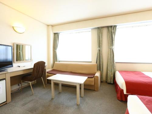 a hotel room with a bed and a desk and a tv at Chino Sky View Hotel in Chino