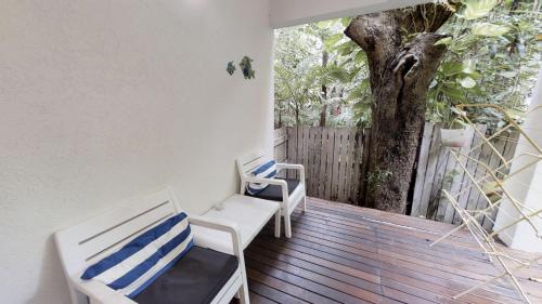 a porch with two chairs and a tree at Silkari The Pavilions in Port Douglas
