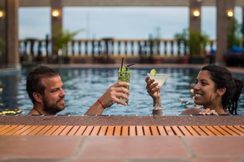 a man and woman in a swimming pool with drinks at Hello Cambodia Boutique in Siem Reap