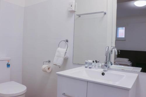 Baño blanco con lavabo y aseo en Glasgow Arms Hotel Ultimo en Sídney