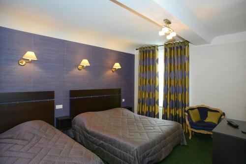 a hotel room with two beds and a chair at Hôtel de La Croix d'Or in Avranches