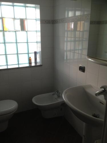 a bathroom with a sink and a toilet and a window at Magnolia House in Taurianova