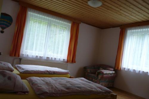 a bedroom with two beds and a chair and windows at Waldcamp Frank in Wildalpen