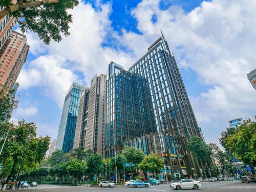 um edifício de vidro alto com carros numa rua da cidade em Vaperse Hotel em Guangzhou