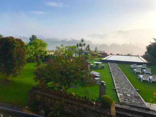 a garden with white tables and chairs on the grass at Elegant Hotel in Kandy